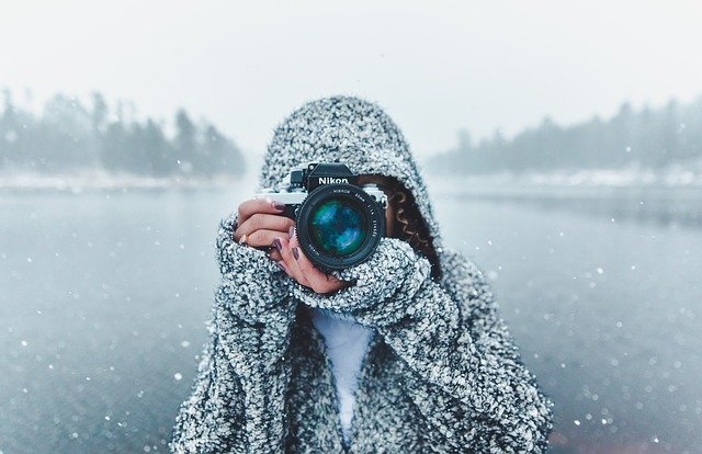 femme qui prend en photo de face avec de la neige en fond